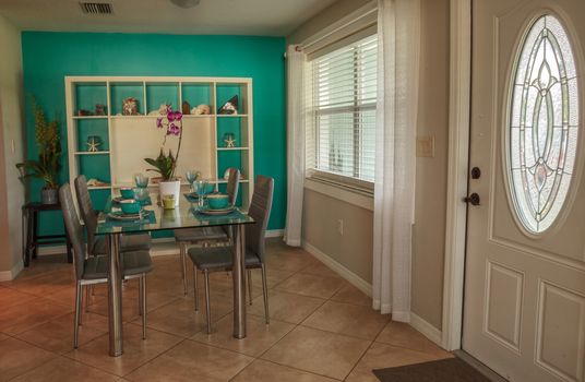 Glass dinner table with aqua blue dishes and a tropical nautical seashell background with a blue wall.