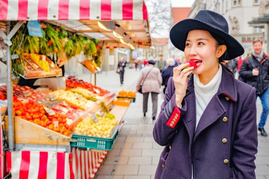 Beautiful Woman eating fresh strawberry on the street market in Germany