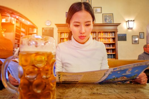 Cute girl drinking beer in Hofbraeuhaus beer house, Munich, Bavaria, Germany