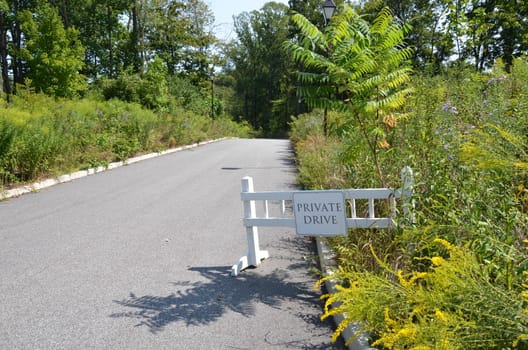 private drive sign or barricade and road with plants