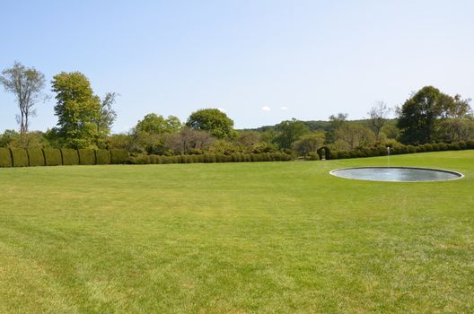 green grass or lawn with water fountain and pond and trimmed bushes