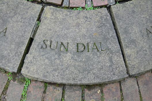 grey stone or rock tile saying sundial with bricks or masonry