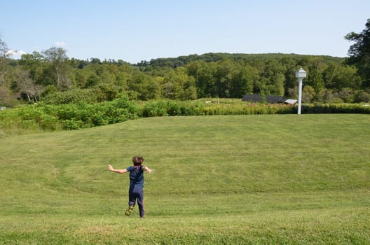 boy child rolling down a grass hill or lawn