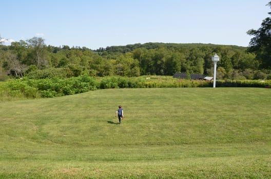 boy child rolling down a grass hill or lawn