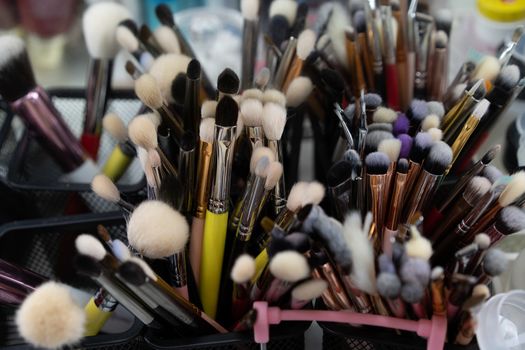 Makeup brushes there A lot of brushes randomly standing in containers at the workplace of a makeup artist or stylist. Beauty concept background