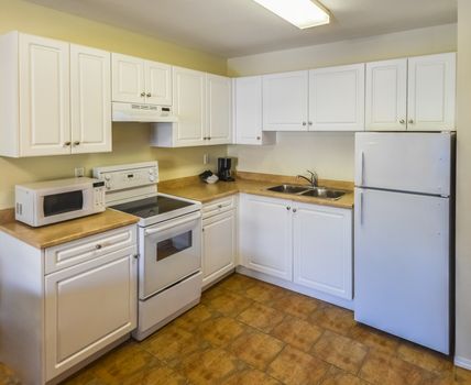 Conventional white kitchen with the table and chairs in dinner area