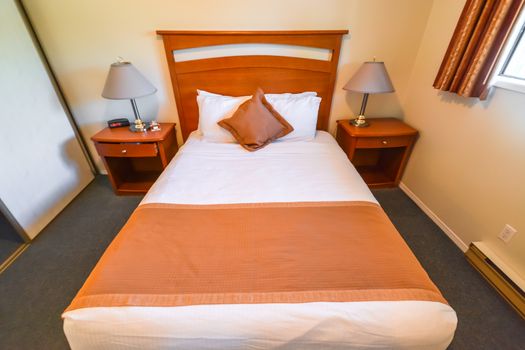 Interior of hotel bedroom with double bed and lamps on bedside tables