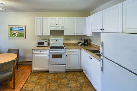 Regular white kitchen with the table and chairs in dinner area