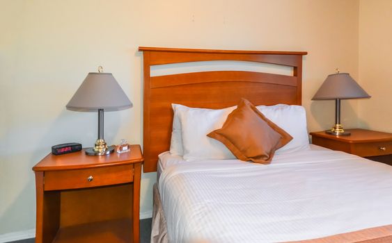 Interior of hotel bedroom with radio watch, perfume vail, and lamps on bedside tables