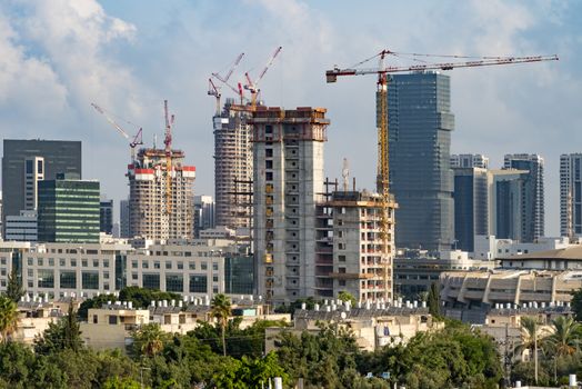 Tel Aviv's skyline high rise construction with cranes and water heaters, Israel. A tall building in a city. High quality photo