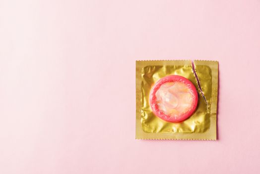 World sexual health or Aids day, Top view flat lay condom in wrapper pack is tear open, studio shot isolated on a pink background, Safe sex and reproductive health concept
