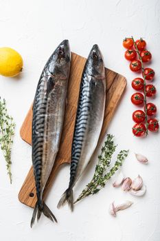 Two mackerel with ingredients on white textured background, top view.