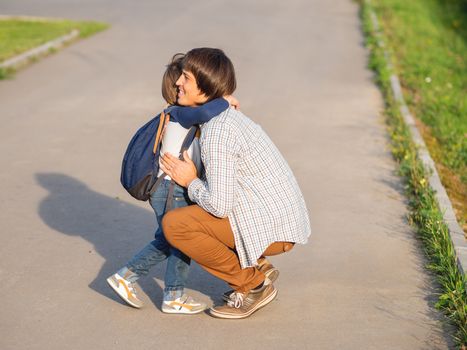 Father takes his son to school. Back to school after summer holidays. Dad and kid hugs on street. Emotional or moral support.