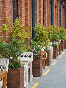 Loft outdoor cafe. Tables and chairs are separate from each other with potted plants and flowers. Social distancing because of coronavirus COVID-19.