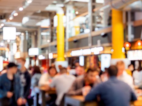 Food court at shopping mall. People are eating without protective masks and social distance. New normal situation after end of coronavirus COVID-19 pandemia. Blurred background.