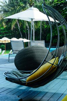 Image of Relaxing chairs with pillows beside swimming pool