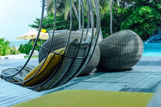 Image of Relaxing chairs with pillows beside swimming pool