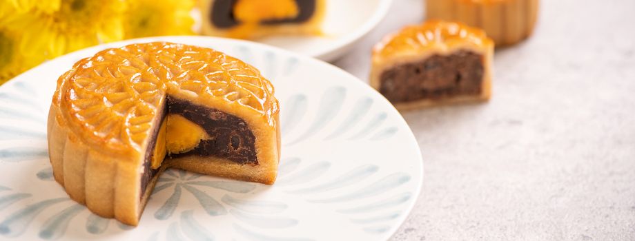 Tasty baked egg yolk pastry moon cake for Mid-Autumn Festival on bright cement table background. Chinese traditional food concept, close up, copy space.