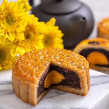 Tasty baked egg yolk pastry moon cake for Mid-Autumn Festival on bright cement table background. Chinese traditional food concept, close up, copy space.
