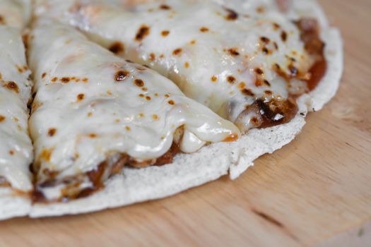 Pizza and cheese on wooden plate on table