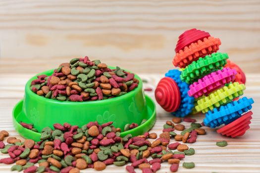 Pet food with rubber toy on wooden background