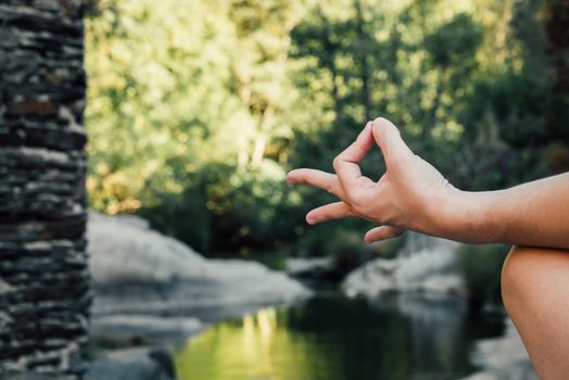 woman's hand doing a mudra in nature