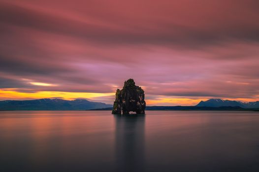 Colorful sunset at the Hvitserkur basalt stack in northern Iceland. Hvitserkur is a spectacular rock in a shape of a dragon or dinosaur drinking water from the ocean. Long exposure.