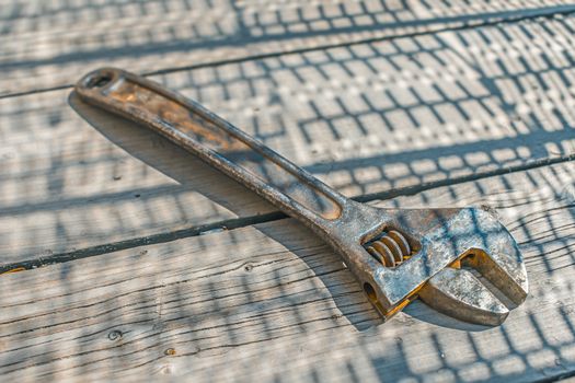 A rusty steel adjustable wrench lies on an old wooden floor