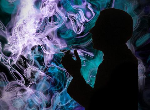 Silhouette of a smoking man on the colorful smoke background - addiction to nicotine. High quality photo