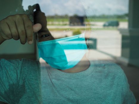 A woman wearing a protective mask looked out from the inside through the glass.