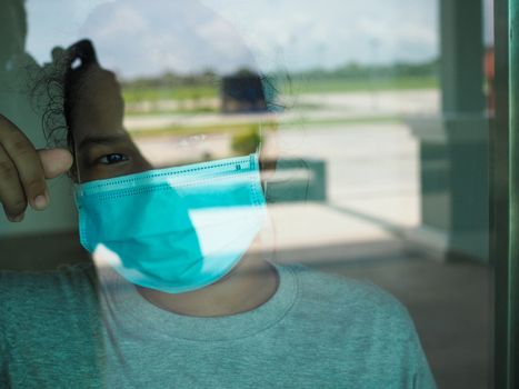 A woman wearing a protective mask looked out from the inside through the glass.