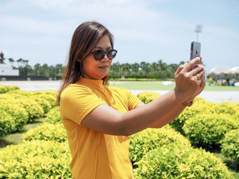 Asian women wearing yellow mats and eyeglasses. Stand selfies in attractions Happily.