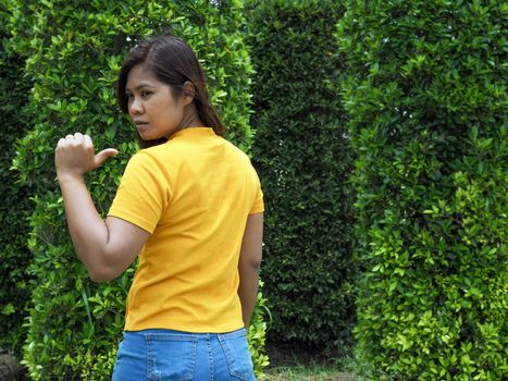 Asian woman Wearing a yellow shirt With a finger pointing at the back of himself.