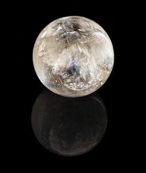 Crystal (quartz) sphere isolated on a black reflective background