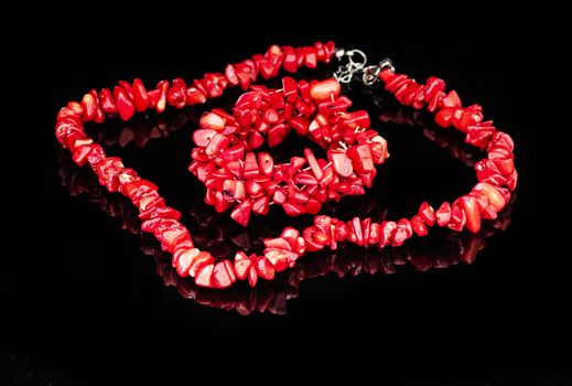 Red coral necklace and bracelet on a black reflective background