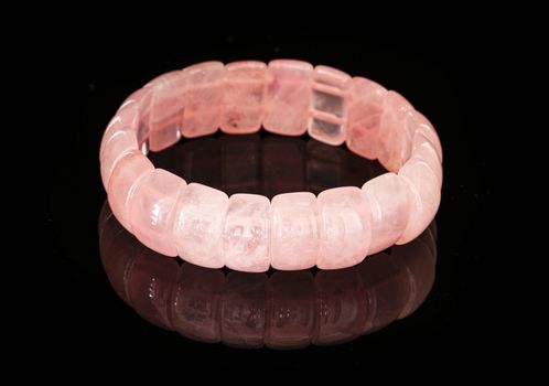 Rose quartz bracelet isolated on a black reflective background