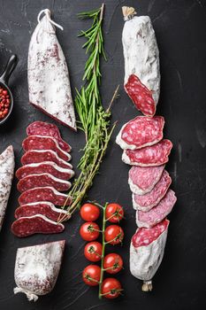 Set of various spanish dry cured salami sausages slices and whole cuts on balck background, flat lay.