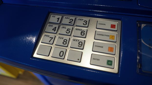 Blue color banking ATM machine and black number on white button keypad.