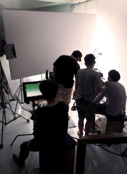 Behind the scene of silhouette film crew team shooting video commercial production and camera equipment in home studio.