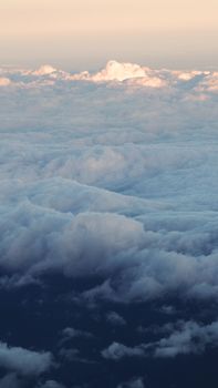 White clouds and blue sky with yellow warm sun light from airplane window.