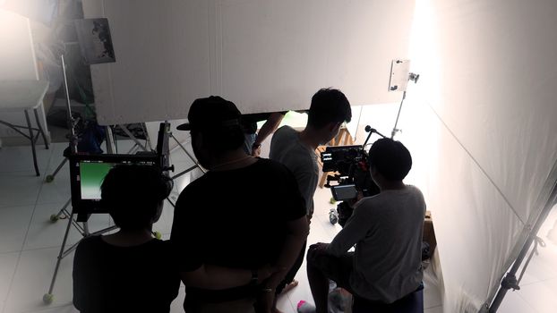 Behind the TV commercial video online shooting scenes and production people are working in silhouette.