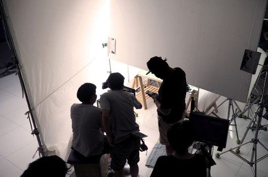 Behind the scene of silhouette film crew team shooting video commercial production and camera equipment in home studio.