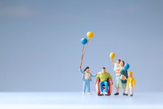 Miniature people Positive family taking care of their disabled Father