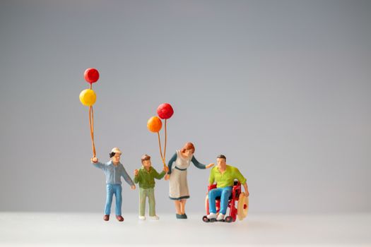 Miniature people Positive family taking care of their disabled Father