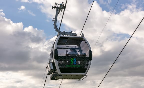 Manzherok resort, Altai Mountains, Russia - August 12, 2020: Low angle shot of cableway with tourists in a cable car on a cloudy sky background