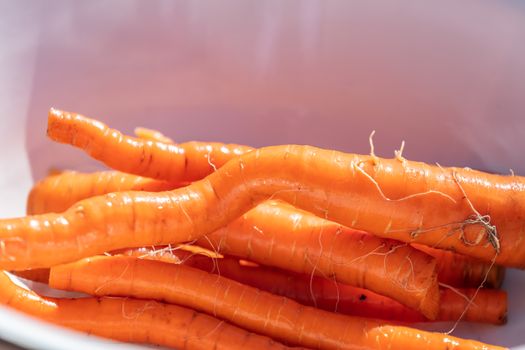 A close up shot of a bunch of clean and washed carrots in a metal bowl. Agriculture and farming concept. Blurred background, copy space.
