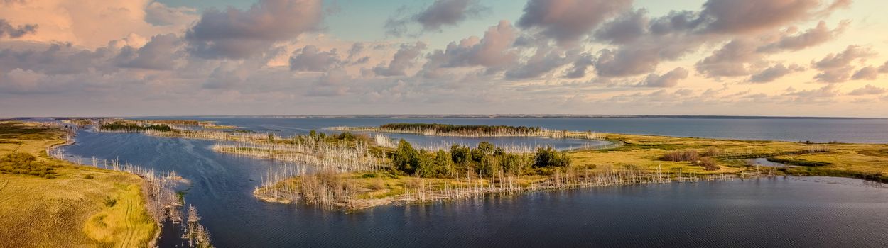 Beautiful panoramic high angle aerial drone shot of islands on one of Gorkoje lakes in Altai Krai, Siberia, Russia. Sunset cloudy sky in the background. Amazing landscape.