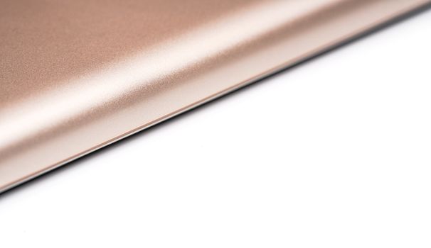 Rose gold colored metal smartphone case, closeup macro detail forming diagonal line with space for text right, abstract technology background.