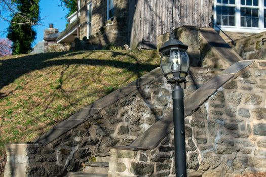 A Black Metal Light Post In Front of Cobblestone Stairs Leading up to a Suburban Home