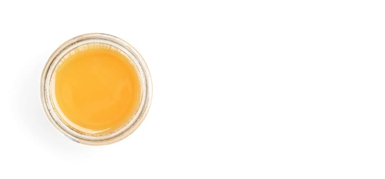 Glass jar with amber coloured honey, view from above, isolated on white background, space for text right side.